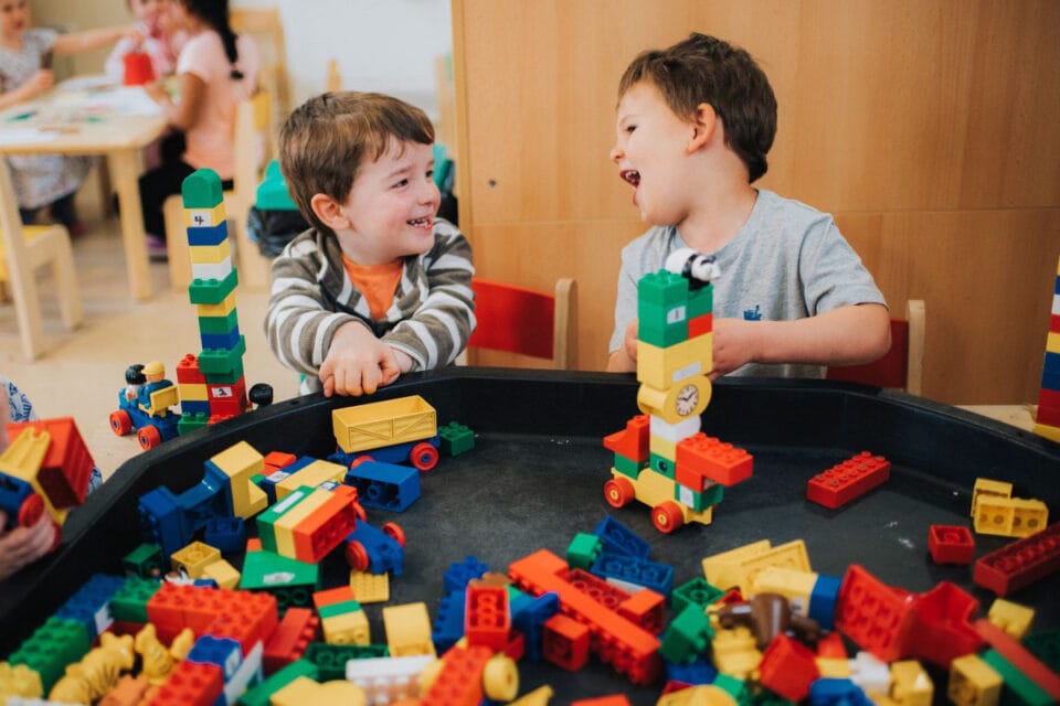 Two young boys laughing as they play with building blocks