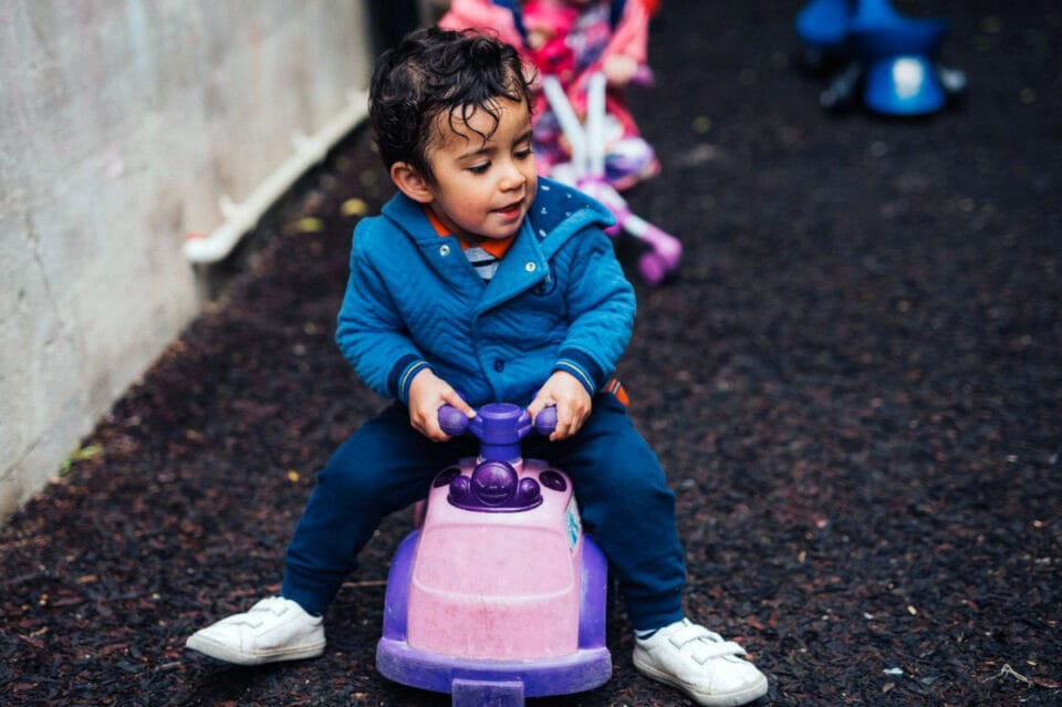 young boy outdoors, riding a toy car